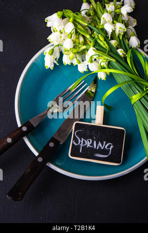 Feastive table setting for holiday Easter dinner decorated with spring snowdrop flowers on rustic table with copy space Stock Photo