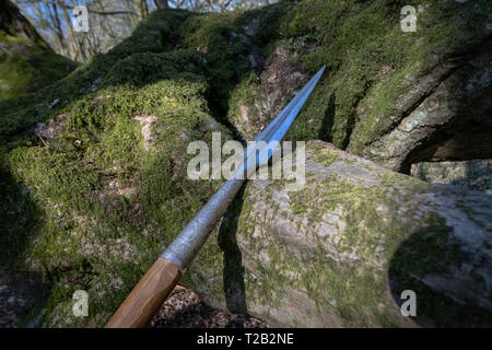 Sharp spear leaning on mossy rocks Stock Photo