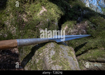 Sharp spear leaning on mossy rocks Stock Photo