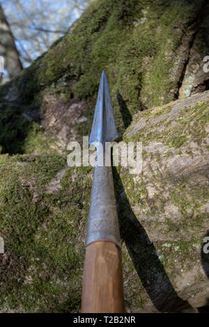 Sharp spear leaning on mossy rocks Stock Photo