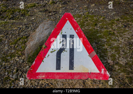 Discarded and damaged road narrows on left sign on the beach Stock Photo