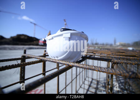 Construction worker helmet on top of a reinforcing iron on a construction site Stock Photo