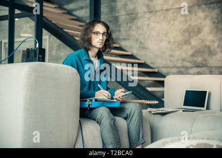 Serious inspired guy in clear glasses being involved in creation process Stock Photo