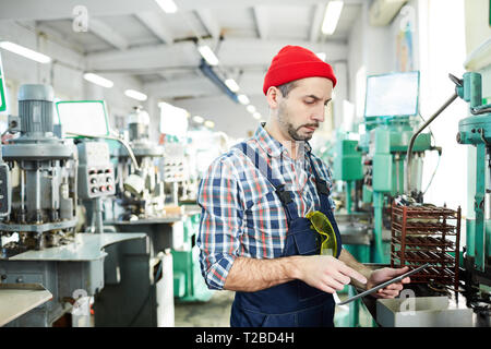 Mature Factory Worker Using Tablet by Machines Stock Photo
