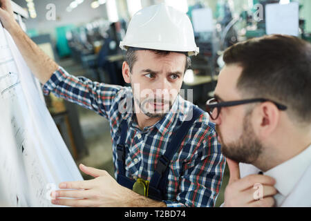 Head and shoulders  portrait of two factory workers discussing  plans and schemes standing in workshop, copy space Stock Photo