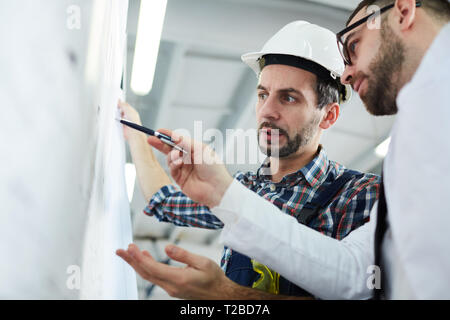 Low angle portrait of two factory workers discussing  plans standing in workshop, copy space Stock Photo