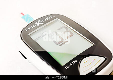 A Keto-Mojo ketone and blood glucose meter is pictured on white, along with a ketone test strip, March 30, 2019, in Coden, Alabama. Stock Photo