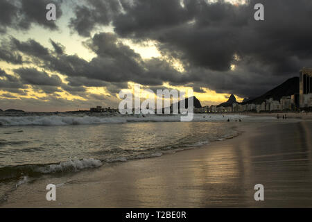 Rio de Janeiro, Brazil - March 29, 2019: Sunset View in Copacabana Beach with Mountains in Horizon and Tall Hotel Building, Rio de Janeiro, Brazil Stock Photo