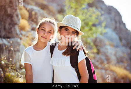 Portrait of a two cute school girls outdoors with backpacks, spending holidays in summer camp, happy active childhood Stock Photo