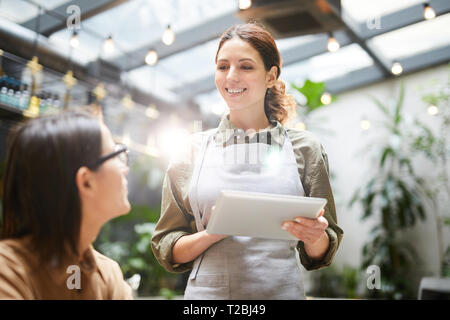 Friendly waitress using tablet to take order Stock Photo