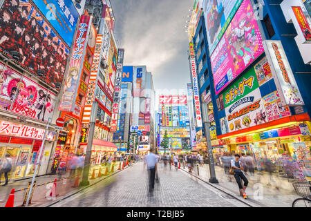 TOKYO, JAPAN - AUGUST 1, 2015: Crowds pass below colorful signs in Akihabara. The historic electronics district has evolved into a shopping area for v Stock Photo