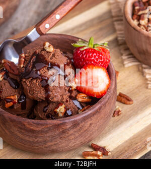 Closeup of a chocolate ice cream sundae with fresh strawberries in a wooden bowl Stock Photo