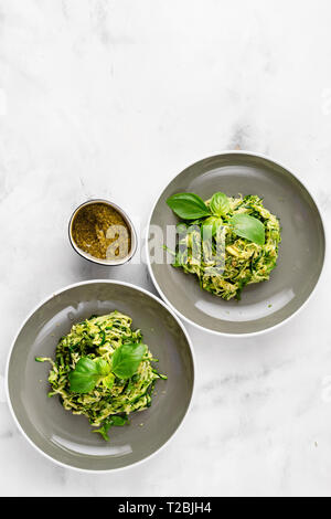 Top view of zucchini vegan pasta in two plates on white background. Copy space Stock Photo