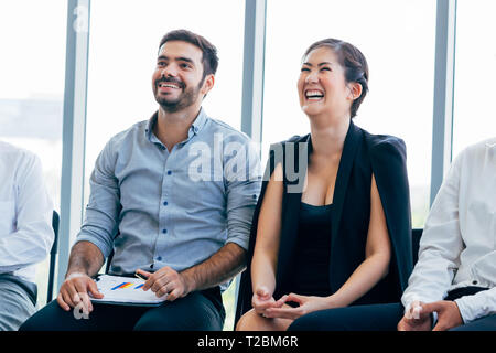 Close-up of businesswoman laughing and having fun listening to presentation and seminar alongside with male business coworker Stock Photo