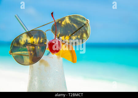 sunglass on cocunut cocktail and sea background on clear sky day Stock Photo