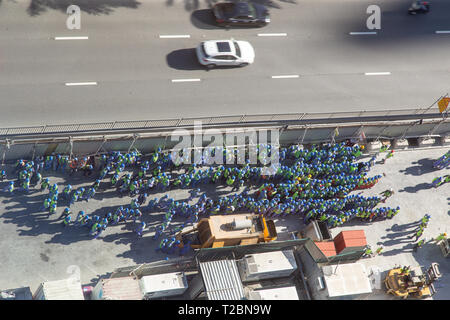 Arial view of a big group of construction workers, grouped on side of the road during a fire drill Stock Photo
