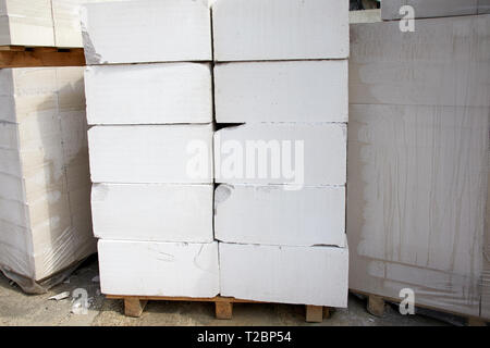 Concrete blocks stacked on pallets outdoors in front of a detached ...