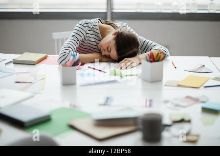 Portrait of contemporary young woman sleeping on table at work , copy space Stock Photo