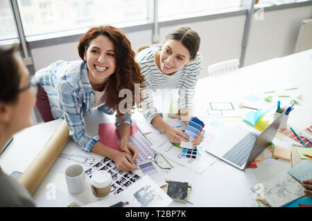 Portrait of two contemporary designers smiling happily while discussing ideas with creative team, copy space Stock Photo