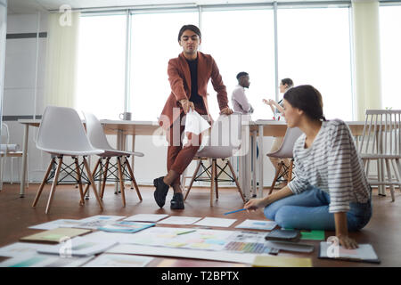 Full length portrait of creative business team planning project on floor in office, focus on foreground, copy space Stock Photo