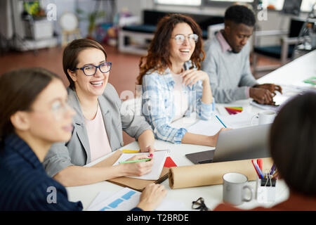 Group of contemporary businesspeople working in meeting focus on woman laughing happily in foreground, copy space Stock Photo
