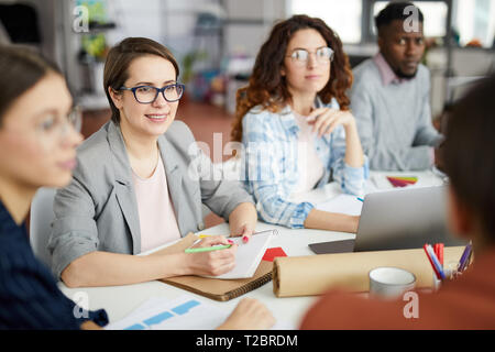 Group of contemporary people working in meeting focus on smiling businesswoman in foreground, copy space Stock Photo