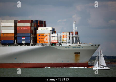 Yacht,passing,Container, Ship, OOCL, Brussels, leaving, Southampton, Terminal, lightly, loaded, box, export, import, The Solent, Cowes, isle of Wight, Stock Photo