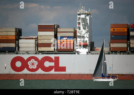 Yacht,passing,Container, Ship, OOCL, Brussels, leaving, Southampton, Terminal, lightly, loaded, box, export, import, The Solent, Cowes, isle of Wight, Stock Photo