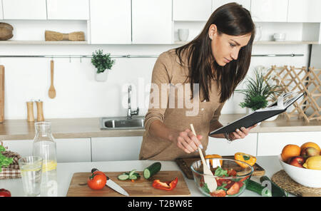 Cooking healthy food in home kitchen concept. Beautiful young woman preparing summer salad Stock Photo