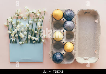 Easter layout with painted eggs and snowdrops in a postal envelope on a pink background. Stock Photo