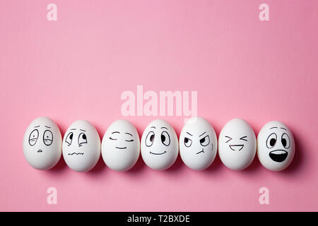 Funny Easter eggs with facial expressions. Eggs with different faces on pink background. Stock Photo