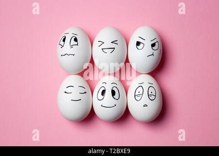 Funny Easter eggs with facial expressions. Eggs with different faces on pink background. Stock Photo