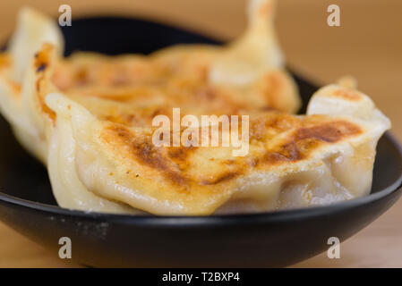 grilled Japanese ravioli served on a black plate, stuffed with meat, gyoza recipe Stock Photo