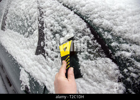 Man's hand cleans snow from a car window Stock Photo