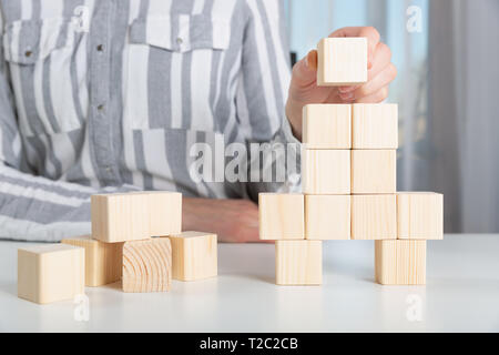 Woman placing last piece to wooden blocks in rocket shape. Start up business launch success concept Stock Photo