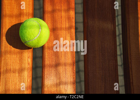 Tennis ball on the bench on court. Concept of sport, healthy lifestyle. Stock Photo