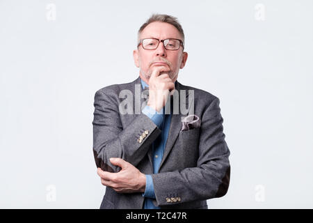 Handsome middle age man in suit and glasses doubt expression. Being confuses concept, uncertain future Stock Photo