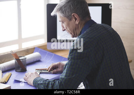 Engineer carpenter working on laptop and sketching project. Stock Photo