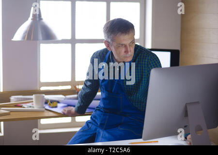 Engineer carpenter working on laptop and sketching project. Stock Photo
