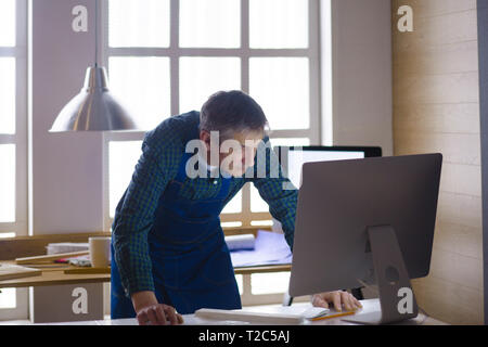 Engineer carpenter working on laptop and sketching project. Stock Photo