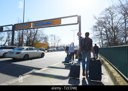 01 April 2019, Berlin: Passengers walk from Tegel Airport with their rolling suitcases to the nearest S-Bahn station. It is a 35-minute walk to Jungfernheide. The BVG is on strike today, Monday. The streets are so crowded that it makes more sense to walk than to queue up at the long queue in front of the taxis or wait for the airport shuttle. Photo: Annette Riedl/dpa Stock Photo