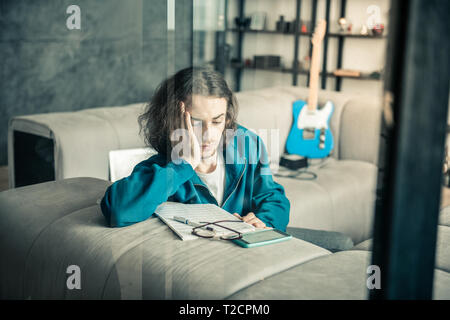 Puzzled dark-haired stylish musician rubbing his face Stock Photo