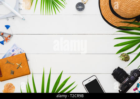 Flat lay traveler accessories on white wooden background with smartphone, palm leaf, seashell, camera and accessories. Summer time travel and vacation Stock Photo