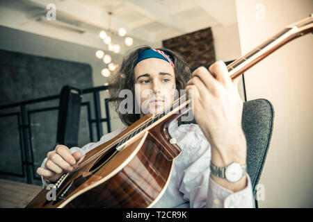 Sad good-looking guy wearing colorful bandana and having tattoo on the face Stock Photo