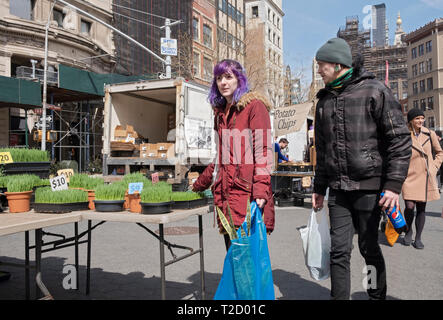 A young man & a lady chack out wheat grass at the Union Square Market in Manhattan, New York City. Stock Photo