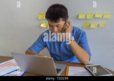 Young businessman sitting in workplace and speaking on the phone Stock Photo