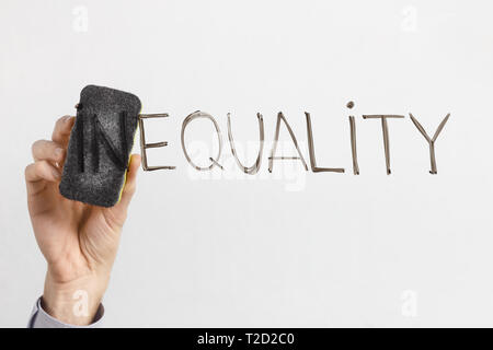 Equality concept. Man cleaning part In in word Inequality with sponge, written on glass board, copy space Stock Photo