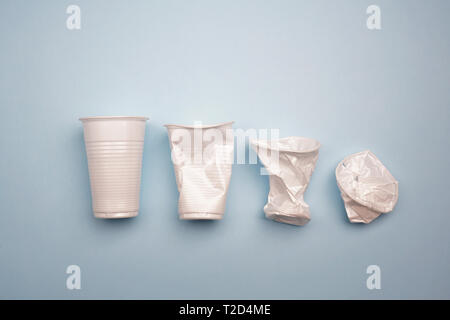 Crumpled plastic cups on bright blue background. Creative minimal environmental problems concept Stock Photo
