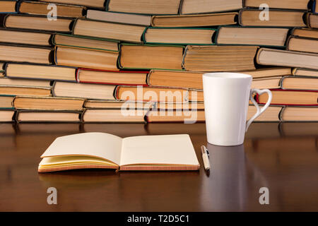cup, notebook and many books on a wooden table Stock Photo