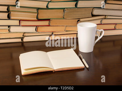 cup, notebook and many books on a wooden table Stock Photo